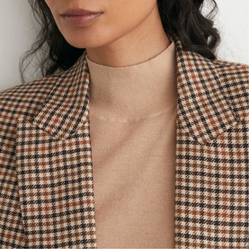 Model wearing Reiss neutral check houndstooth blazer, styled with a beige ribbed turtleneck top. Close-up detail shot.