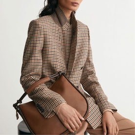 Model carrying a tan structured bag, styled with Reiss neutral check houndstooth blazer and matching trousers