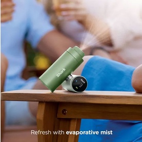 Shark ChillPill 3-in-1 Fan Mist and InstaChill System in Matcha green, emitting cooling mist, placed on a wooden table outdoors.