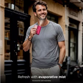 Model with pink handheld evaporative mist fan, styled with grey t-shirt and beige trousers, urban outdoor setting