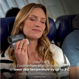 Model with a black handheld cooling device held to neck, seated in an airplane seat, eyes closed