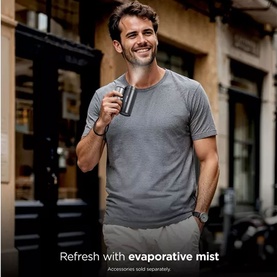 Model wearing grey t-shirt holding a dark grey insulated tumbler cup on a city street