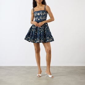 Model wearing Agua Bendita Lima Promesa Mini Dress in multicolour floral print, square neckline, embroidered straps, A-line skirt, styled with white