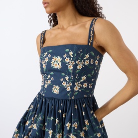 Model wearing Agua Bendita Lima Promesa Mini Dress in multicolour floral print, featuring square neckline and embroidered adjustable straps on navy