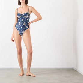 Model wearing Agua Bendita multicolour floral print swimsuit with underwired bust, thin straps, and high-cut leg.