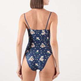 Model wearing Agua Bendita multicolour floral print one-piece swimsuit, navy base with ditsy blooms, thin straps, rear view.
