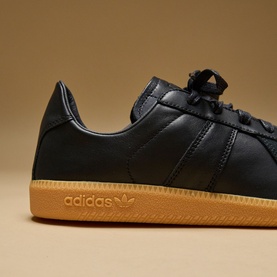 Adidas trainer in core black leather with tonal laces, three-stripe detailing, and contrasting gum rubber sole.