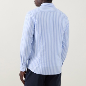 Model wearing Bugatti Soft Oxford Shirt in blue with white vertical stripes, long sleeves, paired with navy trousers. Rear view.