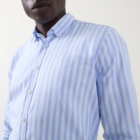 Model wearing Bugatti Soft Oxford Shirt in blue with white vertical stripes, button-down collar and long sleeves visible.