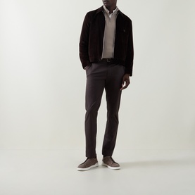 Model wearing Bugatti beige cotton half zip, styled with dark suede jacket, charcoal trousers, and tan trainers.