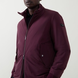 Model wearing Bugatti Black Berry zip-up jacket with funnel neck, sleeve badge detail, and zip pockets, styled over black top.
