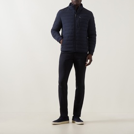 Model wearing Bugatti Zip Pocket Padded Jacket in navy with funnel neck and quilted design, styled with dark slim trousers and grey trainers.