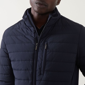 Model wearing Bugatti Zip Pocket Padded Jacket in navy, showing quilted front, funnel neck, and chest zip pocket detail.