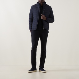 Model wearing Bugatti Navy Zip Pocket Padded Jacket with funnel neck and quilted design, styled with black trousers and navy trainers.