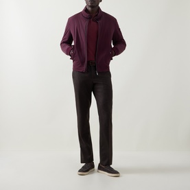 Model wearing Bugatti Blackberry polo with a zip-up bomber jacket and dark tailored trousers, styled with grey suede trainers.