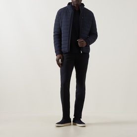 Model wearing Bugatti Logo Polo Shirt in navy, styled with a navy quilted jacket, dark trousers, and grey slip-on shoes.