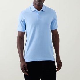 Model wearing Bugatti light blue polo shirt, short sleeves and three-button placket, styled with black trousers.