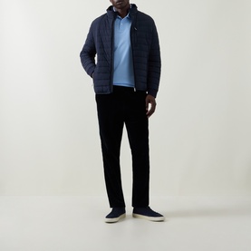 Model wearing Bugatti light blue polo with navy quilted jacket, black cord trousers and navy trainers.