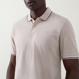 Model wearing Bugatti beige polo shirt with contrast tipped collar and cuffs, small embroidered logo on chest