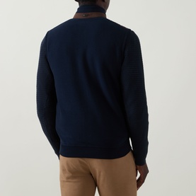 Model wearing Bugatti blackberry cotton sweatshirt, back view, with textured knit detail and collar, styled with tan trousers.