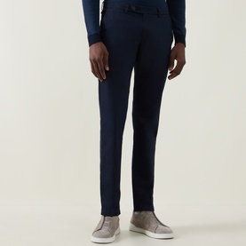 Model wearing Bugatti Lux Slim-Leg Chinos in navy, slim-fit with clean hems, styled with a navy top and grey slip-on shoes.