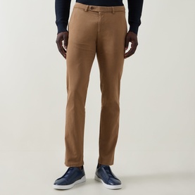 Model wearing Bugatti brass chino trousers in slim fit, styled with navy blue trainers and a navy knit jumper.