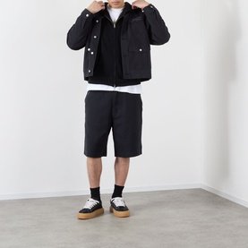Model wearing black hooded jacket and black shorts, styled with white tee, black socks, and black trainers with gum soles