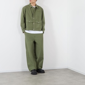 Model wearing Emporium 89 Ripstop Logo Jacket in green with matching green trousers, white underlayer and black shoes.