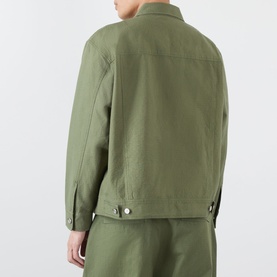 Model wearing Emporium 89 Ripstop Logo Jacket in green, showing rear view with buttoned cuffs and straight hem, styled with matching green trousers.