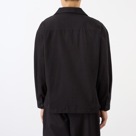 Model wearing Emporium Logo Pullover Polo Shirt in black, back view, showing dropped shoulders, long sleeves and buttoned cuffs, styled with black