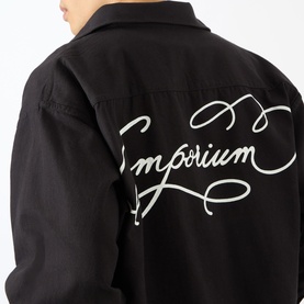 Model wearing Emporium Logo Pullover Polo Shirt in black, showing white cursive Emporium logo embroidery across the back.