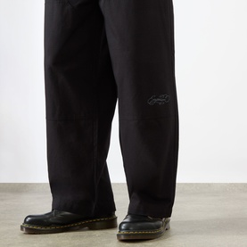 Model wearing Emporium Ripstop Fatigue Wide Leg Denim Trousers in black, wide-leg silhouette with embroidered logo detail, styled with black leather