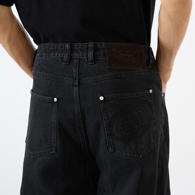 Model wearing Emporium Stitch Wide Leg Jeans in black, showing rear five-pocket detail with stitched logo and custom silver hardware.
