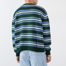 Model wearing Emporium Stripe Fisherman Knit Sweater in green, heavyweight crew neck with multicolour horizontal stripes, styled with light blue