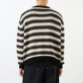 Model wearing Emporium Stripe Fisherman Knit Sweater in black, showing rear view with multicolour horizontal stripes and ribbed hem, styled with dark