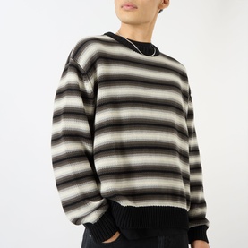 Model wearing Emporium Stripe Fisherman Knit Sweater in black, heavyweight crew neck with bold horizontal stripes, layered over a black top.