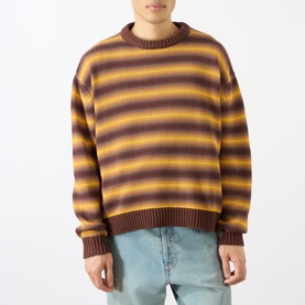Model wearing Emporium Stripe Fisherman Knit Sweater in black, heavyweight crew neck with multicolour stripe pattern, styled with light blue jeans.