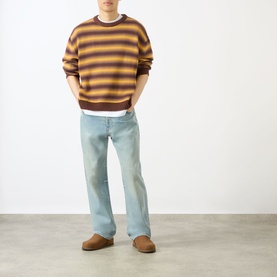 Model wearing Emporium Stripe Fisherman Knit Sweater in black, styled with light-wash jeans and brown suede slippers.