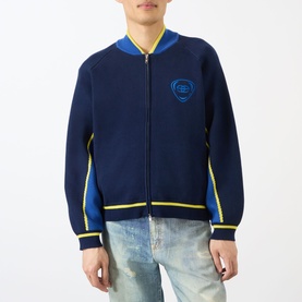 Model wearing Emporium Boca Logo Knitted Zip Sweater in navy with blue bomber collar, yellow trim detail, and chest logo patch, styled with light