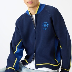 Model wearing Emporium Boca Logo Knitted Zip Sweater in navy with yellow trim, blue bomber collar, and embroidered chest logo, styled over white tee.
