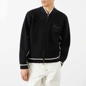 Model wearing Emporium Boca Logo Knitted Zip Sweater in black with bomber collar, contrast white trim, and chest logo patch, styled with white
