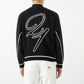Model wearing Emporium Boca Logo Knitted Zip Sweater in black, showing large jacquard back logo, bomber collar, and stripe trim detail.