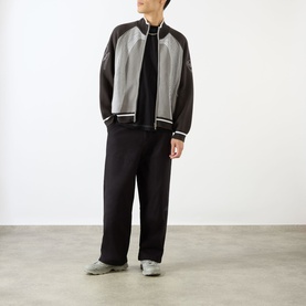 Model wearing Emporium E90 Logo Knitted Zip Sweater in grey, styled with black wide-leg trousers and grey trainers.