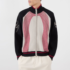 Model wearing Emporium E90 Logo Knitted Zip Sweater in navy with red and ecru jacquard knit, funnel collar, double zip, styled with cream trousers