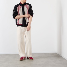 Model wearing Emporium E90 Logo Knitted Zip Sweater in navy, styled with cream wide-leg trousers and red loafers.