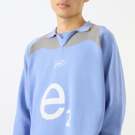Model wearing Emporium Henry Logo Knitted Sweater in baby blue with grey yoke panel, jacquard 'e' logo, and open polo collar.