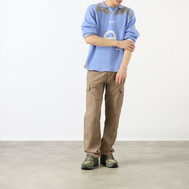 Model wearing Emporium Henry Logo Knitted Sweater in baby blue with open polo collar, styled with tan cargo trousers and hiking shoes.