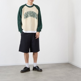 Model wearing Emporium Logo Mohair Sweater in green, cream colourblock with raglan sleeves, styled with black shorts and leather shoes.