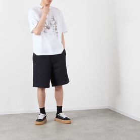 Model wearing Emporium Armour Logo T-Shirt in white with front graphic print, styled with black shorts and black-and-tan trainers.