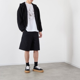 Model wearing Emporium Armour Logo T-Shirt in white with black zip hoodie, wide-leg black shorts, and black low-top trainers with gum soles.